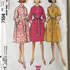 May include: Vintage McCall's pattern 7554 for Misses' robes. The pattern features three robe designs: one with a floral print, one solid pink, and one yellow. The pattern size is small, 10-12.