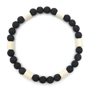 May include: A black and white beaded bracelet with black lava rock beads and white cylindrical beads.
