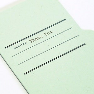 May include: A light green file folder with a black tab and the text "SUBJECT: Thank You" printed on the front.