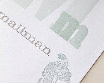 May include: A green and white card with the letter "M" and the word "mailman" printed on it. A cartoon image of a mailman carrying a bag of mail is below the text.