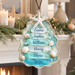 May include: A hanging ornament shaped like a Christmas tree, crafted from layers of sea glass in shades of blue and white. It features a white starfish at the top, small seashells, and pearls. The names Emma, Sophia, William, Henry, Olivia, and 2026 are printed.