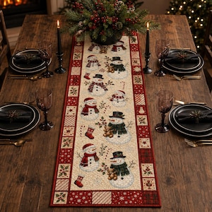 May include: A rectangular fabric table runner featuring a cream-colored center panel with a repeating pattern of snowmen, candy canes, and stockings, bordered by a red and green patchwork design with snowflake and holly motifs.
