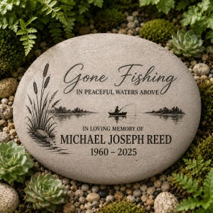 Könnte beinhalten: Ein glatter, hellgrauer Gedenkstein mit einer Gravur, die eine Person beim Angeln in einem Boot auf einem See mit Schilf zeigt. Der Text lautet: Gone Fishing IN PEACEFUL WATERS ABOVE IN LOVING MEMORY OF MICHAEL JOSEPH REED 1960 - 2025.