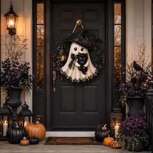 May include: A decorative Halloween wreath featuring a white ghost wearing a black witch hat and holding a small black cat. The wreath is adorned with dark foliage, black roses, and a miniature lantern, all centered on a dark door.