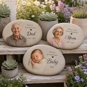 May include: Three oval memorial stones featuring engraved portraits and text. One stone shows a man with 'Forever in our hearts Dad 1942-2023', another a woman with 'Always loved Never forgotten Mom 1945-2024', and the third a baby with 'Forever in our hearts Baby 2024'.