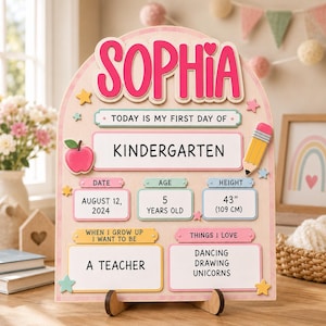 May include: A wooden arch-shaped sign for a first day of kindergarten with the name SOPHIA in pink. It features sections for date 12 August 2024, age 5 years old, height 109 cm, career goal as a teacher, and interests including dancing, drawing, and unicorns.