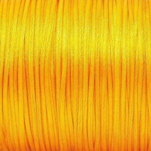 May include: A spool of bright yellow waxed cord. The cord is tightly wound and has a smooth, shiny finish.