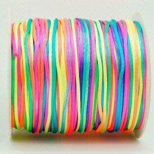 May include: A spool of colorful waxed cord, featuring a rainbow of bright colors, including pink, orange, yellow, green, blue, and purple.