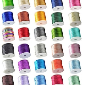 May include: A collection of 30 spools of colorful thread, each wound with a different color of thread. The spools are arranged in rows of five, with each row containing a different color scheme. The thread is likely used for crafts, sewing, or jewelry making.