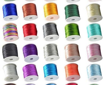May include: A collection of 30 spools of colorful thread, each wound with a different color of thread. The spools are arranged in rows of five, with each row containing a different color scheme. The thread is likely used for crafts, sewing, or jewelry making.