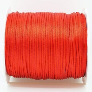 May include: A spool of bright orange waxed cord. The cord is wound tightly around the spool and is ready to be used for crafting projects.