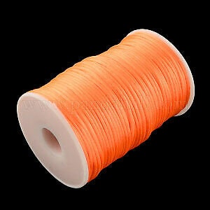 May include: A spool of bright orange waxed cord, perfect for jewelry making, macrame, or crafts.
