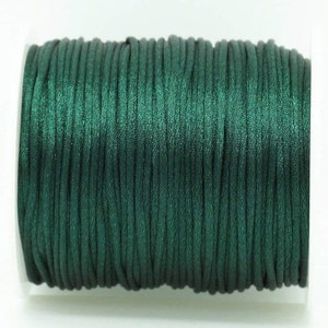 May include: A spool of dark green satin cord.