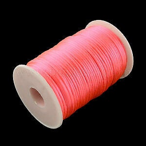 May include: A spool of bright pink satin cord, perfect for crafting and jewelry making.