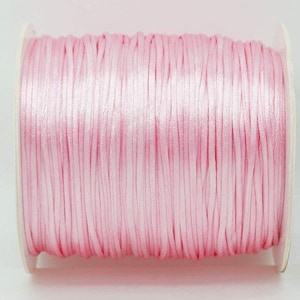 May include: A spool of light pink satin cord.