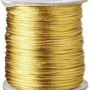 May include: A spool of gold metallic cord, a type of thread used for crafts and jewelry making.