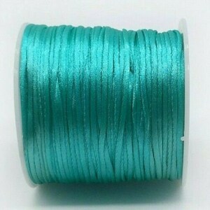 May include: A spool of teal blue satin cord.