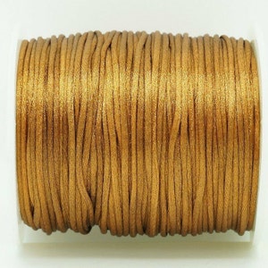 May include: A spool of gold metallic cord, a type of thread used for jewelry making and crafts.