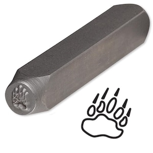 May include: A metal stamp with a bear paw print design. The stamp is used to create impressions on metal.