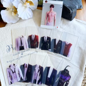 May include: A collection of clear acrylic cards featuring images of formal wear, including suits and a vest, and a shirtless man. Some cards have text that reads "Please take one" and "Thank you for coming to this very simple special day."