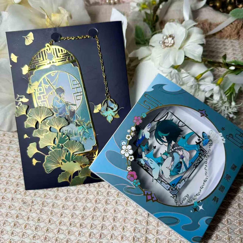 May include: Two decorative bookmarks with a fantasy theme. One is a gold-colored metal bookmark with a chain and a blue and gold pendant. The other is a blue box with a character illustration and butterflies.