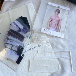 May include: Clear acrylic photo holders with images of a male figure and various clothing items. The photo holders are designed to resemble an Instagram post. The clothing items include shirts and other garments.