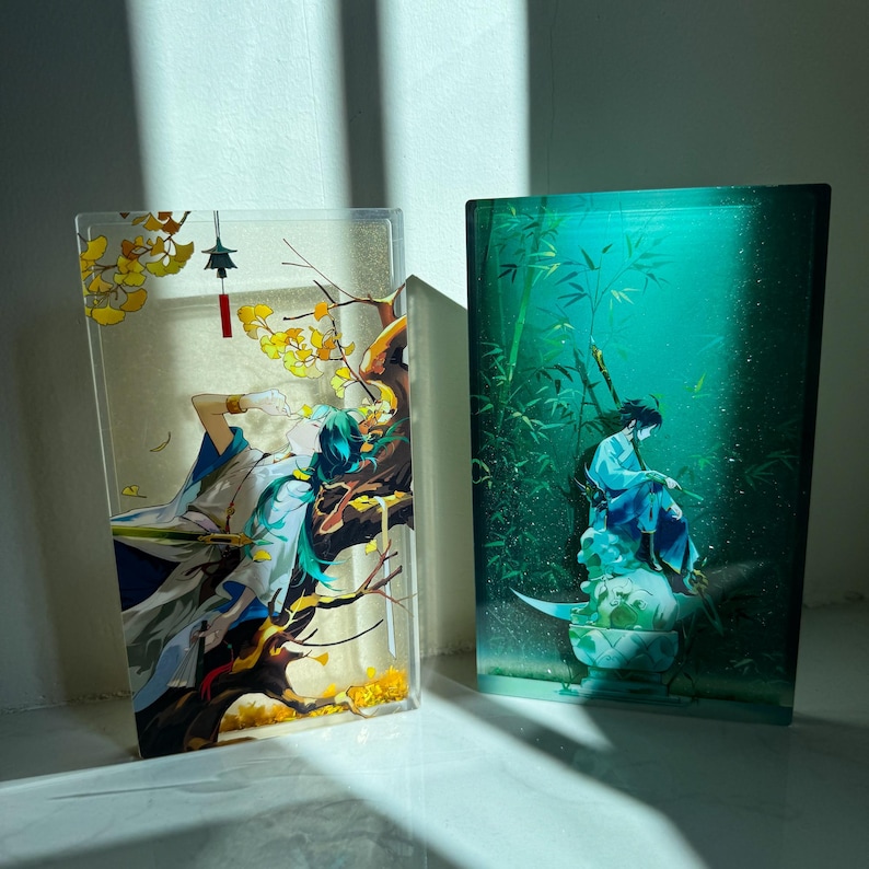 Peut inclure: Deux panneaux d&eacute;coratifs en acrylique avec des &oelig;uvres d'art d'inspiration asiatique. L'un repr&eacute;sente une figure aux cheveux turquoise et aux v&ecirc;tements bleus au milieu d'un feuillage jaune. L'autre montre une figure en tenue bleue dans une for&ecirc;t de bambous.
