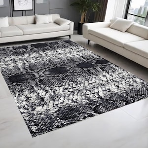 May include: Black and white area rug with a snakeskin pattern. The rug has a modern design and is perfect for adding a touch of style to any room.