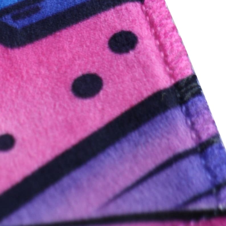 Peut inclure: Gros plan sur un tissu rose, bleu et violet avec des rayures noires et des pois noirs. Le tissu a une texture douce et duveteuse.