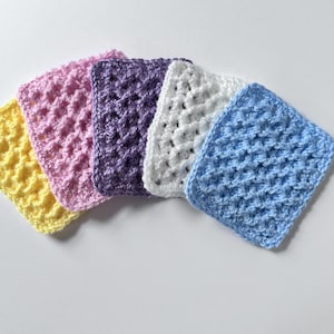May include: A collection of six crocheted squares in various colors: yellow, pink, purple, white, and blue. Each square has a textured, raised pattern. The squares are arranged in a fan shape, showcasing the different colors and textures.