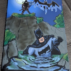 May include: A comic book cover featuring Batman in a blue and gray costume, partially submerged in water. The cover is titled "Night of the Scarecrow" and features a shadowy figure of the Scarecrow in the background.