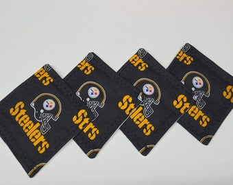 May include: Four black and yellow fabric coasters with the Pittsburgh Steelers logo and the word "Steelers" repeated on each coaster.