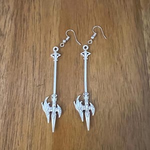 May include: A pair of silver earrings with a sword design. The swords have intricate details and are attached to silver hooks.