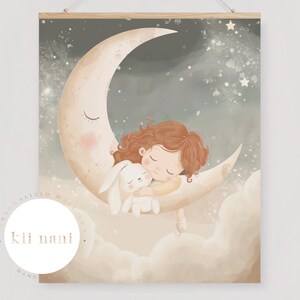 Op de afbeelding: Een grillige wandkunstprint met een kind en een konijn die knuffelen op een halve maan. De illustratie heeft een zacht kleurenpalet van beige, perzik en grijs, met sterren op de achtergrond. De print wordt vastgehouden door een houten hanger.