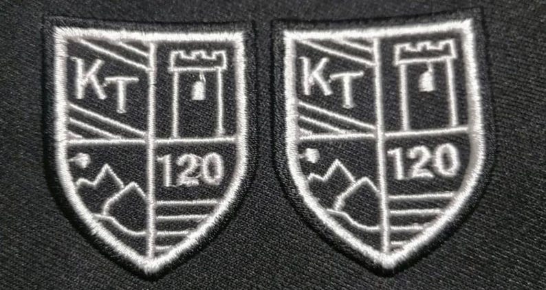 May include: Two white embroidered patches with a black background. Each patch features a shield with a tower, the letters "KT", and the number "120".