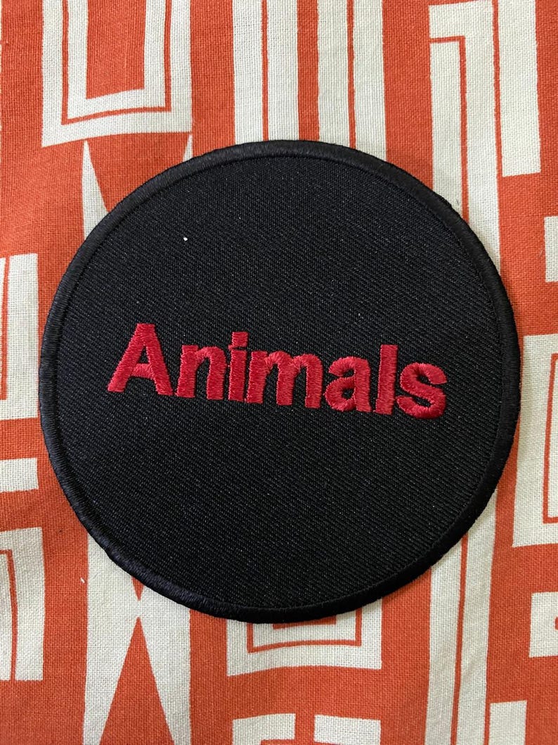 May include: A black circular patch with red embroidered text that reads "Animals".