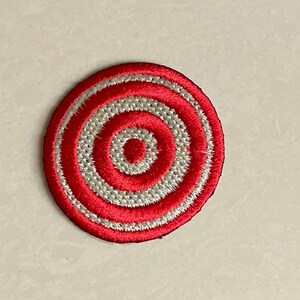 May include: Red and white embroidered circle patch with concentric circles.