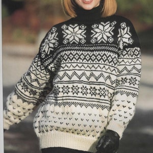 Pode incluir: Um suéter branco e preto com padrão e gola alta preta. O suéter tem um design de floco de neve e um padrão geométrico.