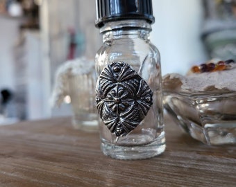 reclaimed fine silver charm on glass needle bottle, stitched diamond corner tie downs effect