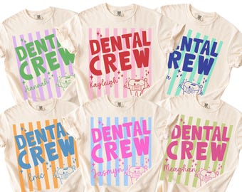 May include: A collection of six cream-colored t-shirts, each featuring the text DENTAL CREW in bold letters over vertical stripes. Each shirt displays a unique name and a graphic of a cartoon tooth wearing a face mask and holding dental tools.