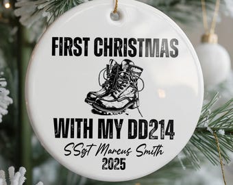 May include: White ceramic Christmas ornament with the text "FIRST CHRISTMAS WITH MY DD214" and the name "SSgt Marcus Smith 2025". The ornament features a black and white illustration of combat boots.