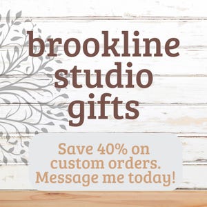 May include: White wood background with brown text that reads "brookline studio gifts". Below the text is a white rectangle with brown text that reads "Save 40% on custom orders. Message me today!"