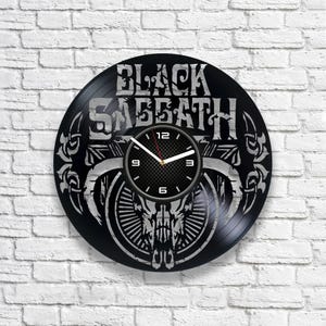 Op de afbeelding: Black Sabbath vinyl platen klok met een schedel en hoorns ontwerp. De wijzerplaat van de klok is zwart met witte cijfers en wijzers.