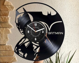 Könnte beinhalten: Schwarze Schallplattenuhr mit einer Silhouette von Batman. Das Zifferblatt der Uhr ist weiß mit schwarzen Zahlen und Zeigern. Die Schallplatte ist mit "BATMAN" beschriftet.