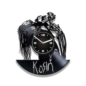 Pode incluir: Relógio de vinil preto com a silhueta de uma pessoa cantando em um microfone. O mostrador do relógio é preto com números e ponteiros brancos. O disco está assinado com "Kosin".
