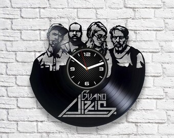 May include: A black vinyl record clock featuring a silhouette of four people and the band name "Guano Apes". The clock face is white with black numbers and hands.