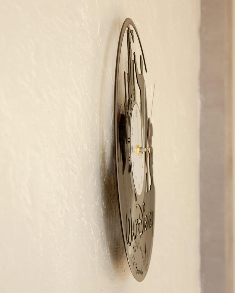 May include: A black vinyl record clock featuring a silhouette of Cinderella's castle and the text "Walt Disney" with a white clock face.