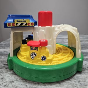 May include: A white ceramic mug with a black handle and the text "But First, Coffee" in a black, bold font. The mug is on a white surface.