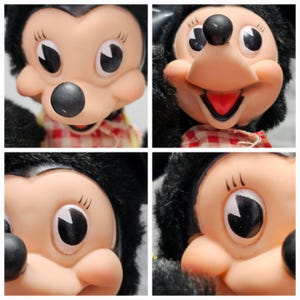 May include: Close-up of a vintage Minnie Mouse doll. The doll has a black nose, black fur around the face, and large eyes. She is wearing a red and white checkered bow tie. The doll's face is made of a light peach-colored material.