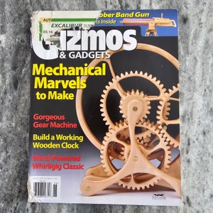 May include: The cover of "Gizmos & Gadgets" magazine features a wooden gear machine. The magazine's title is in large white letters with a black background. The cover also includes the text "Mechanical Marvels to Make" and "Build a Working Wooden Clock."